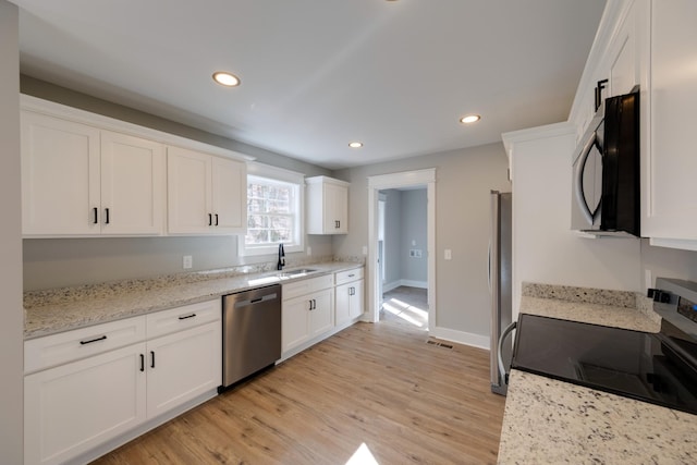 kitchen featuring sink, appliances with stainless steel finishes, light stone countertops, white cabinets, and light wood-type flooring