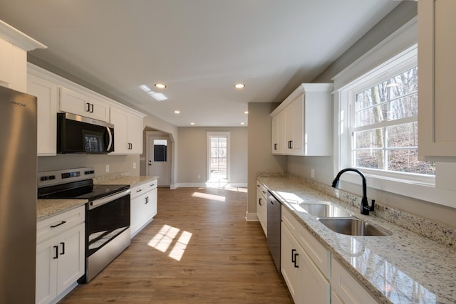 kitchen featuring sink, dark wood-type flooring, stainless steel appliances, light stone counters, and white cabinets