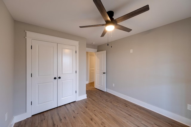 unfurnished bedroom with ceiling fan, a closet, and light wood-type flooring