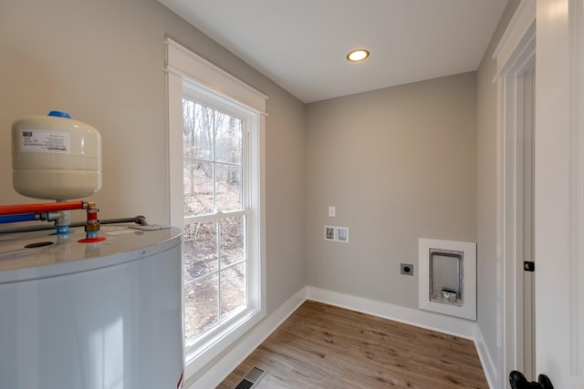 clothes washing area with hookup for an electric dryer, hookup for a washing machine, hardwood / wood-style floors, and water heater