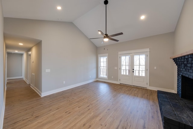 unfurnished living room featuring ceiling fan, lofted ceiling, a fireplace, and light hardwood / wood-style floors