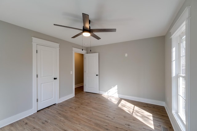 unfurnished bedroom featuring ceiling fan, multiple windows, and light hardwood / wood-style flooring