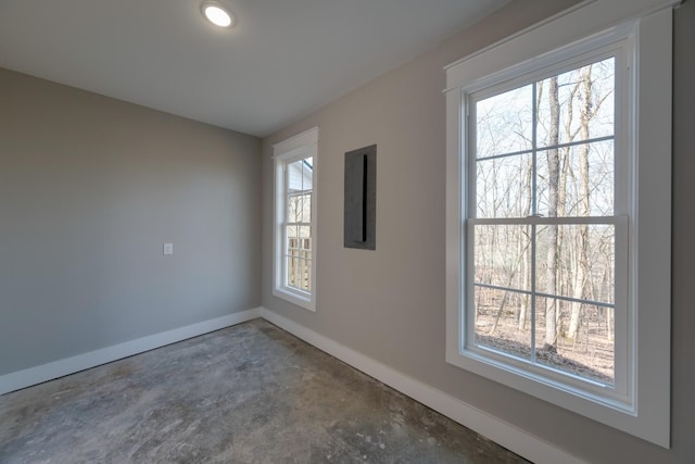 empty room with concrete flooring, plenty of natural light, and electric panel