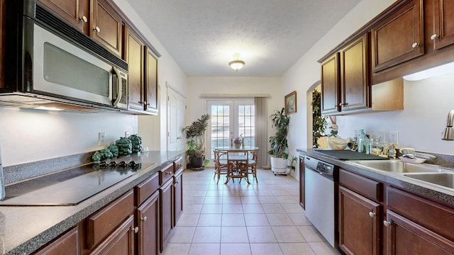 kitchen featuring appliances with stainless steel finishes, sink, light tile patterned floors, a textured ceiling, and french doors