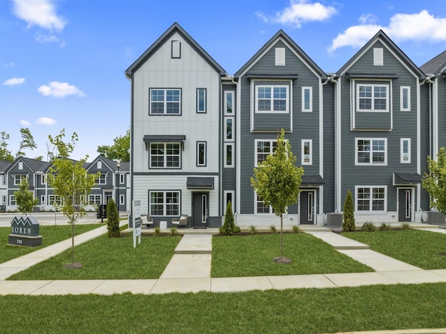 townhome / multi-family property featuring cooling unit and a front yard