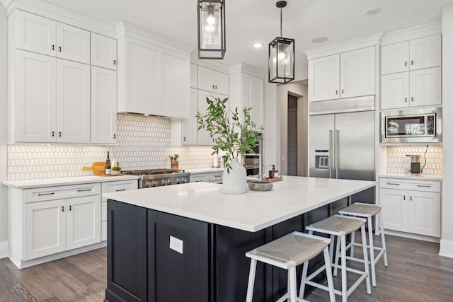 kitchen featuring hanging light fixtures, built in appliances, white cabinets, a kitchen island, and dark hardwood / wood-style flooring