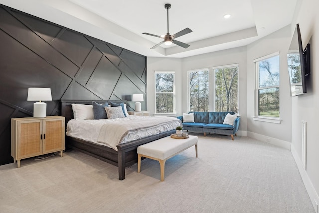 carpeted bedroom featuring ceiling fan and a tray ceiling