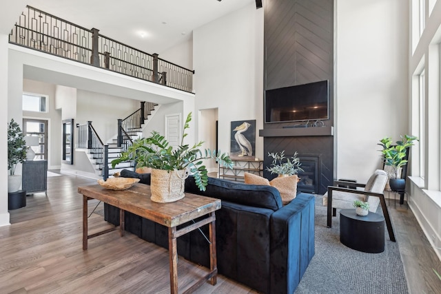 living room featuring a large fireplace, hardwood / wood-style floors, and a high ceiling