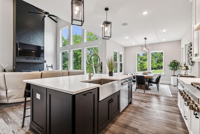 kitchen featuring dark hardwood / wood-style floors, pendant lighting, white cabinetry, an island with sink, and sink