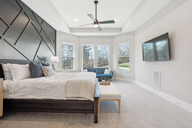 bedroom featuring a raised ceiling, ceiling fan, and carpet flooring