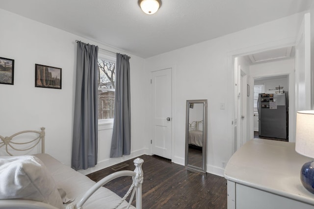 bedroom with dark hardwood / wood-style floors, a textured ceiling, and stainless steel refrigerator