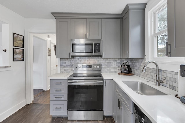 kitchen featuring tasteful backsplash, appliances with stainless steel finishes, sink, and gray cabinetry