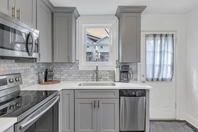 kitchen featuring stainless steel appliances, sink, decorative backsplash, and gray cabinetry