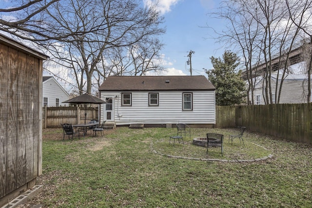 back of property with a lawn and a fire pit