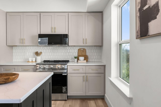 kitchen with gray cabinetry, stainless steel range, and a wealth of natural light