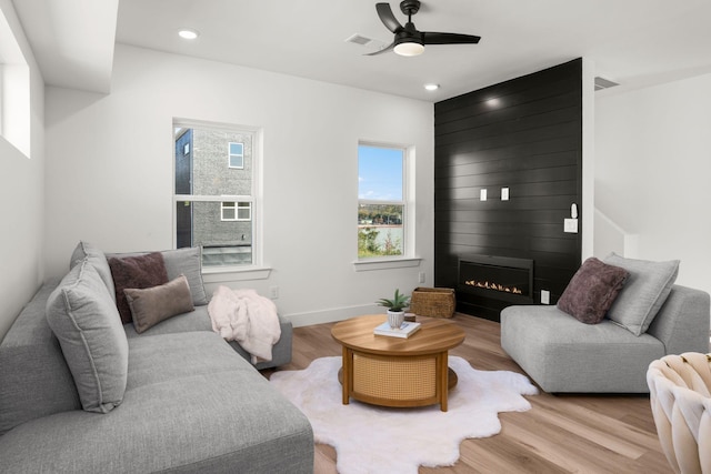 living room with ceiling fan, a fireplace, and light wood-type flooring