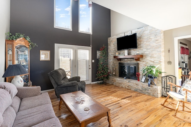 living room featuring a towering ceiling, a fireplace, and hardwood / wood-style floors