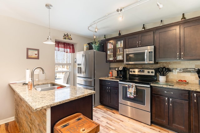 kitchen featuring dark brown cabinetry, sink, light stone counters, and stainless steel appliances