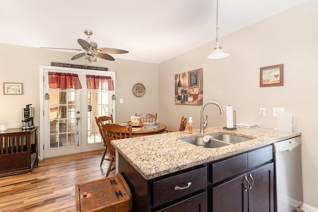 kitchen with hanging light fixtures, sink, stainless steel dishwasher, and light stone counters