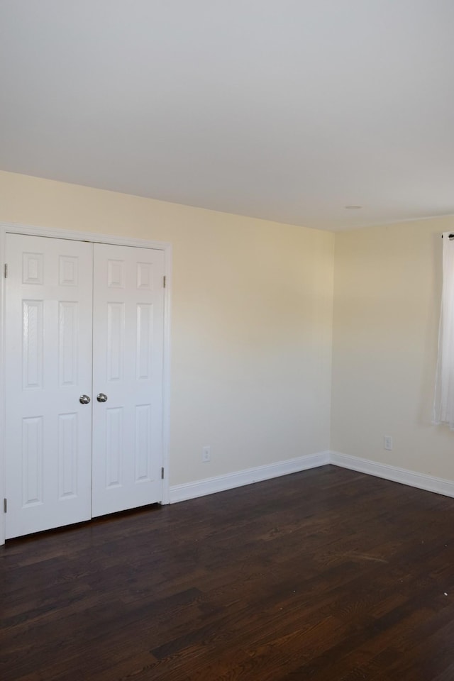 unfurnished bedroom featuring dark hardwood / wood-style flooring and a closet