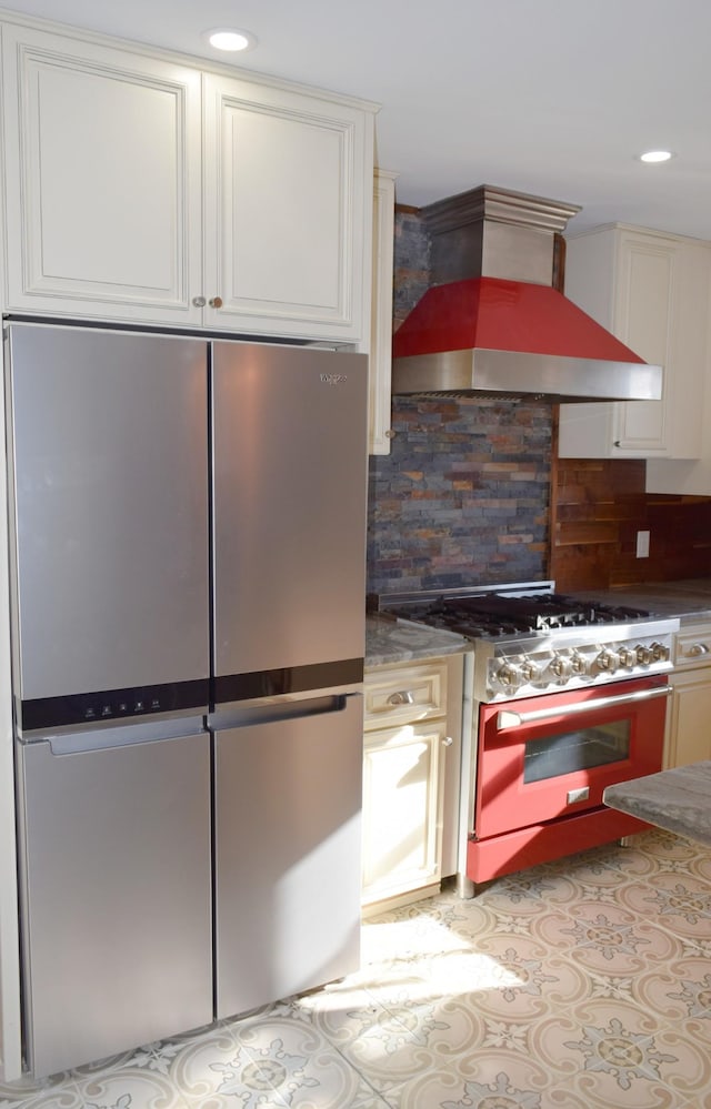 kitchen featuring stainless steel fridge, gas range oven, and wall chimney exhaust hood