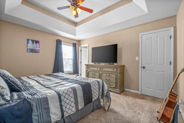 carpeted bedroom with a tray ceiling and ceiling fan