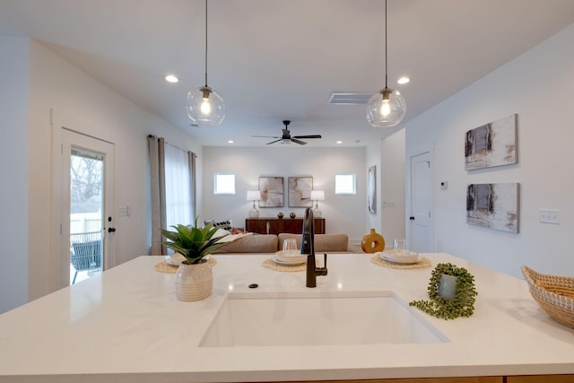 kitchen with ceiling fan, decorative light fixtures, a kitchen island with sink, and sink