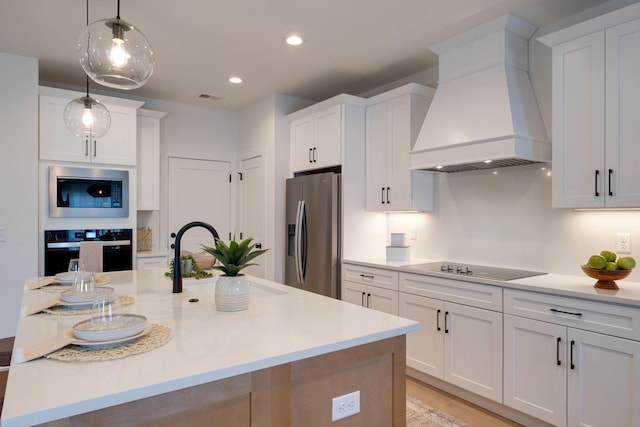 kitchen featuring sink, premium range hood, white cabinetry, black appliances, and decorative light fixtures