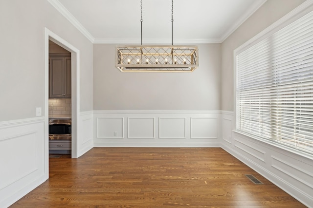 unfurnished dining area with hardwood / wood-style flooring, ornamental molding, and a healthy amount of sunlight