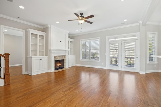 unfurnished living room with hardwood / wood-style floors, ornamental molding, and ceiling fan