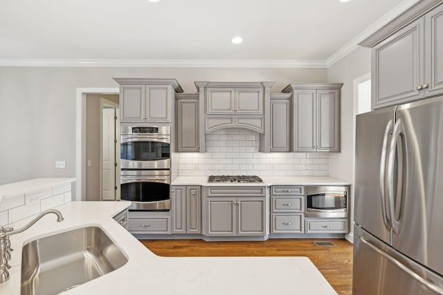 kitchen featuring ornamental molding, appliances with stainless steel finishes, sink, and gray cabinetry