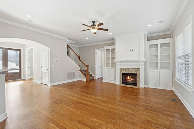 unfurnished living room with wood-type flooring, ornamental molding, and ceiling fan