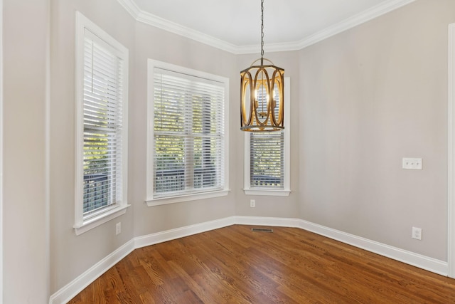 spare room with an inviting chandelier, wood-type flooring, and ornamental molding