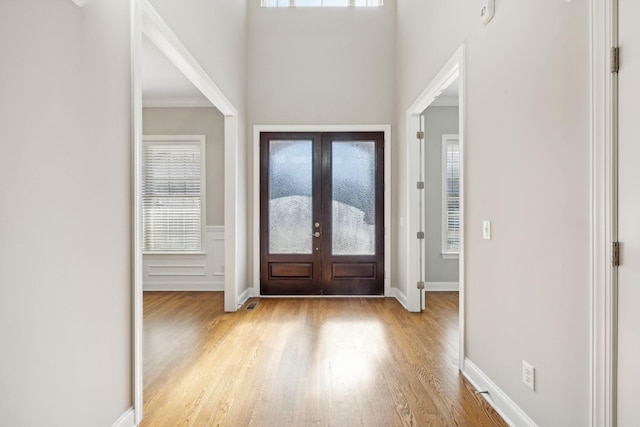 foyer featuring ornamental molding, light hardwood / wood-style floors, and french doors