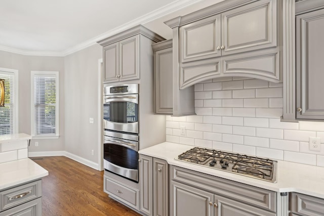 kitchen with ventilation hood, ornamental molding, appliances with stainless steel finishes, dark hardwood / wood-style floors, and decorative backsplash