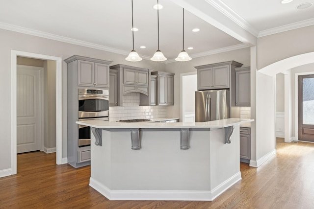 kitchen with gray cabinetry, a kitchen breakfast bar, and appliances with stainless steel finishes