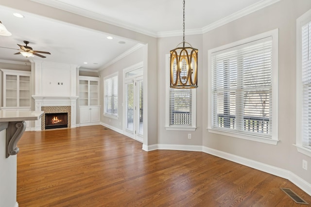 unfurnished living room featuring crown molding, dark hardwood / wood-style floors, built in shelves, and ceiling fan with notable chandelier