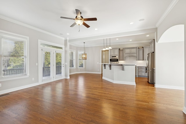 unfurnished living room featuring crown molding, wood-type flooring, and ceiling fan