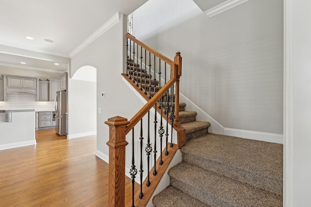 staircase with hardwood / wood-style flooring and crown molding