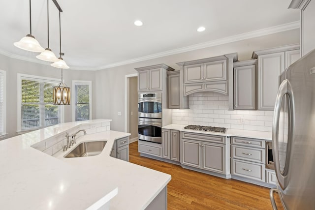 kitchen with stainless steel appliances, hanging light fixtures, sink, and gray cabinetry