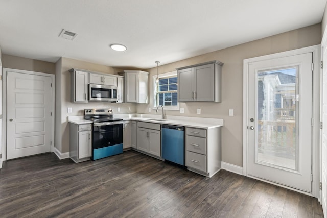 kitchen featuring pendant lighting, appliances with stainless steel finishes, gray cabinets, and sink