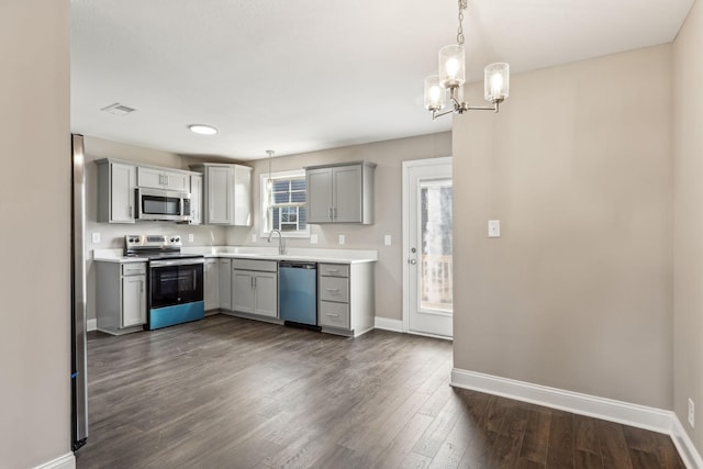 kitchen featuring stainless steel appliances, hanging light fixtures, sink, and gray cabinetry