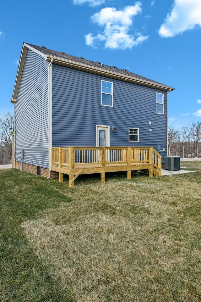 rear view of house with central AC, a deck, and a lawn