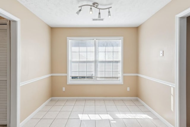 unfurnished room with light tile patterned flooring and a textured ceiling