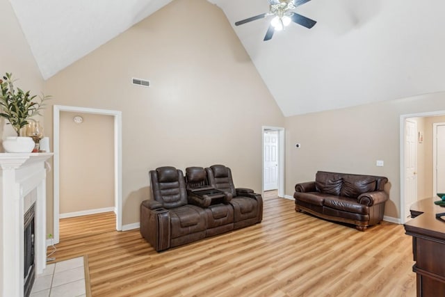 living room with ceiling fan, a fireplace, high vaulted ceiling, and light hardwood / wood-style floors