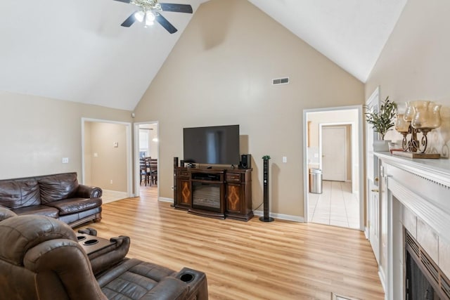 living room featuring high vaulted ceiling, ceiling fan, and light wood-type flooring