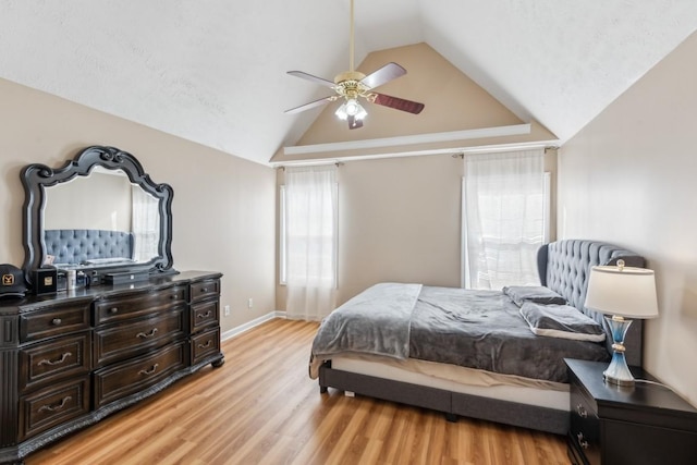 bedroom with ceiling fan, lofted ceiling, and light wood-type flooring