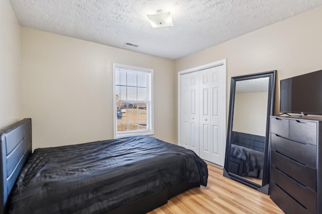 bedroom with light hardwood / wood-style floors, a closet, and a textured ceiling