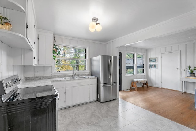 kitchen with appliances with stainless steel finishes, sink, a wealth of natural light, and white cabinets