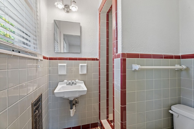 bathroom featuring sink, tile walls, and toilet